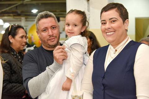 Fotografia Dos Pais Da Manuella Mostrando A Cruz No Colar Da Filha Na Paróquia São Judas Tadeu em São Paulo, SP Feita por Priscila Felix Fotógrafa de Casamentos, Ensaios e Família'