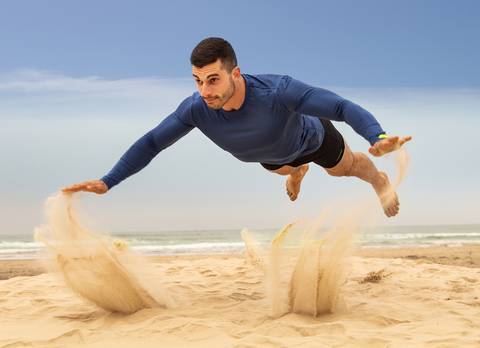 Homem em salto horizontal na praia'