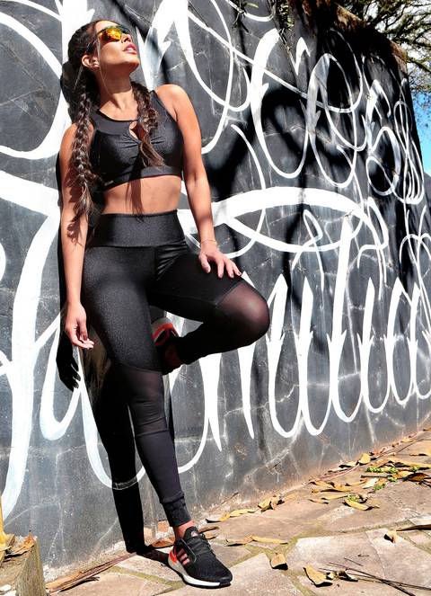 Mulher com roupa fitness apoiada no muro'