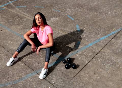 Mulher com roupa fitness sentada na quadra'