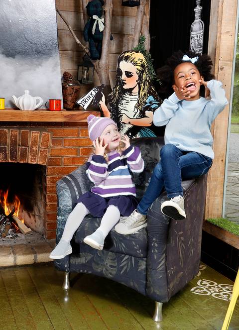 Meninas com roupa de inverno ao lado da lareira'