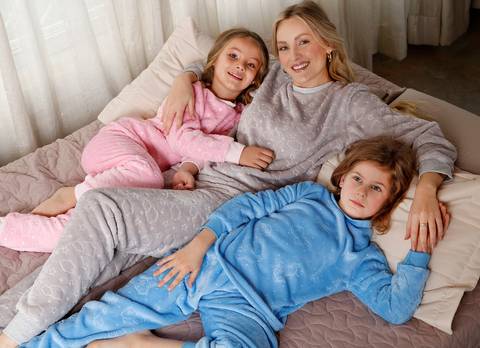 Mãe e filhos de pijama na cama'