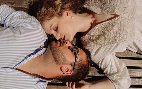 Sessão fotográfica de casal deitados num banco'