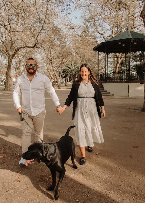 Foto de gravidez em casal no parque com cão'