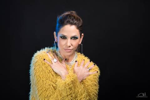 modelo-con-abrigo-amarillo-con-manos-cruzadas-maquillaje-intenso-pelo-recogido'