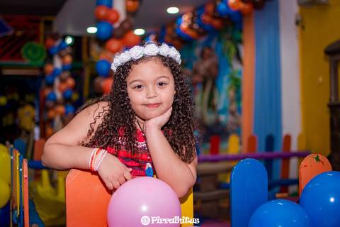 Lara fazendo pose com mão no queixo debruçada num cercadinho de madeira da casa de festas espaço kids no valqueire, rio de janeiro.'