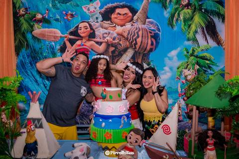 Fotografia de família na mesa do bolo com a personagem vivo Moana.'