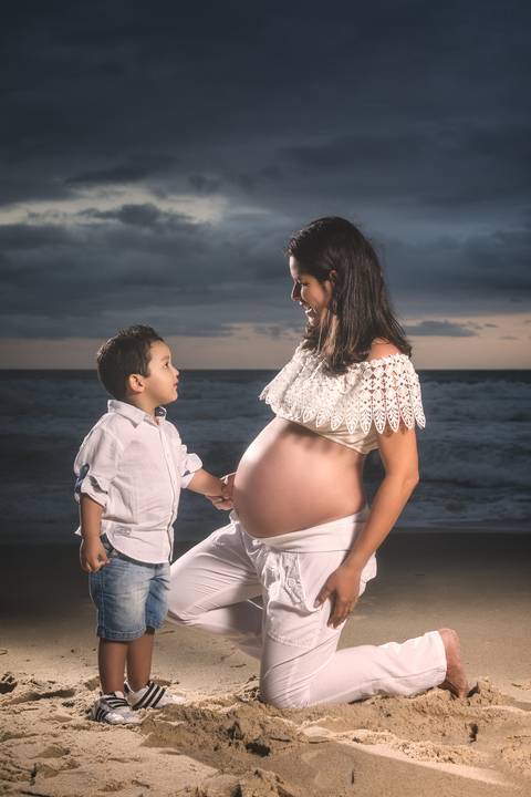 Ensaio Gestante na praia de  Grumari, Rio de Janeiro ao pôr-do-sol, mãe e filho se olhando e sorrindo.'