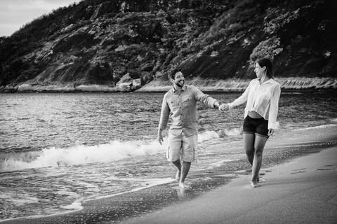 Casal Rafael e Maria Joana caminhando na praia vermelha, ensaio gestante em preto e branco, foto de jl tavares, para o site pirralhitus.'