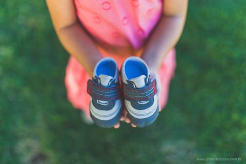 menina segurando sapatinhos de bebê'