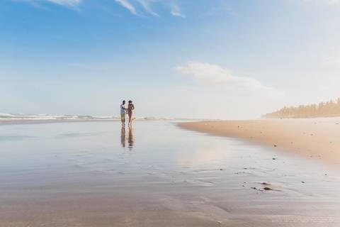 casal gestante caminhando na praia'