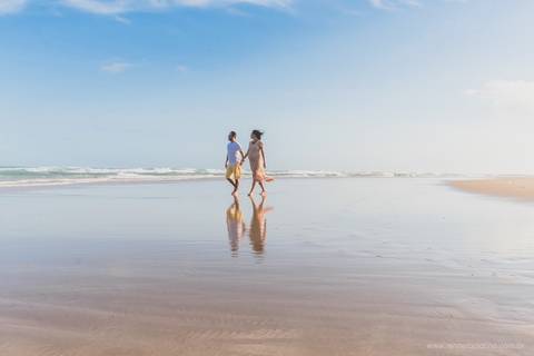 casal gestante caminhando na praia'