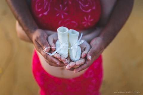 casal segurando sapatinho de bebê'