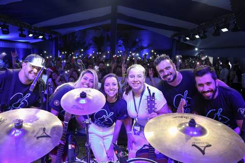 Banda do GPA, composta por funcionários, posando para uma foto no palco com o público visível ao fundo, celebrando a performance no Evento de Fim de Ano 2024 na sede em São Paulo.'