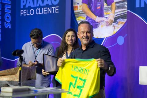 Diretor do GPA recebendo uma camisa da seleção brasileira personalizada com seu nome no palco, em homenagem à sua saída da empresa durante o Evento de Fim de Ano 2024 em São Paulo.'