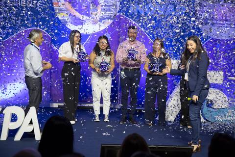 Funcionários premiados no palco do Evento de Fim de Ano GPA 2024, celebrando sob uma chuva de confetes e papéis picados, em um momento de euforia na sede em São Paulo.'