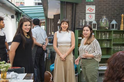 Convidados do evento Westwing + ELLE no Restaurante Chou em São Paulo, conversando e rindo, desfrutando da atmosfera leve e agradável da confraternização.'