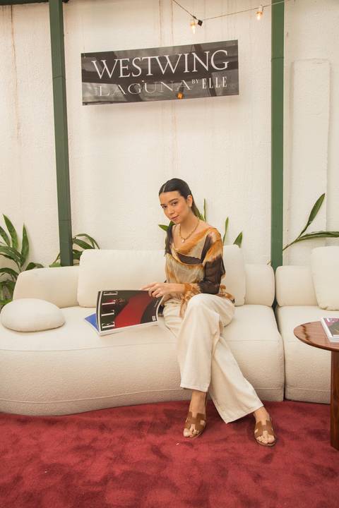 Participante posando para foto no sofá modular da Westwing, folheando a revista ELLE, capturando um momento de estilo e interação no evento em Moema, São Paulo.'