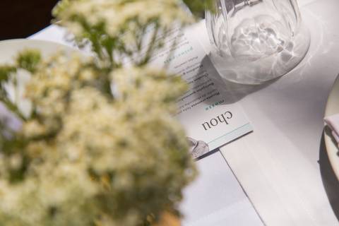 Detalhe do menu do evento no Restaurante Chou em São Paulo, com o nome 'Chou' em destaque e uma flor elegantemente desfocada ao fundo, indicando a sofisticação gastronômica.'
