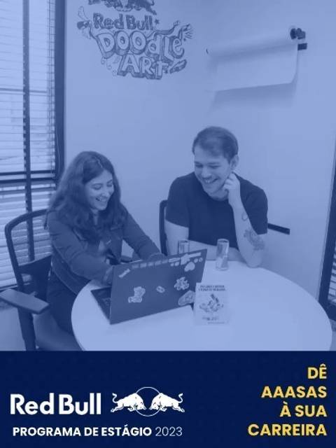 Banner do programa de estágio Red Bull Brasil 2024 com dois estagiários trabalhando em colaboração em uma mesa com um notebook, ambos sorrindo, no ambiente de trabalho moderno da sede em São Paulo.'
