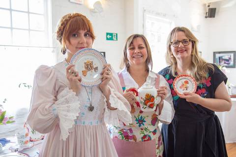 Julia Danesi, Carla Pernambuco e uma convidada posando juntas, sorrindo e exibindo as louças da nova coleção Westwing, durante o evento de lançamento no Restaurante Carlota em São Paulo.'