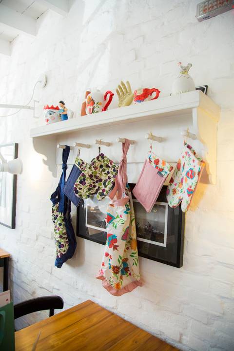 Conjunto de aventais e luvas da coleção de Carla Pernambuco em parceria com a Westwing, exibindo os detalhes e o design dos acessórios de cozinha, no evento de lançamento no Restaurante Carlota em São Paulo.'