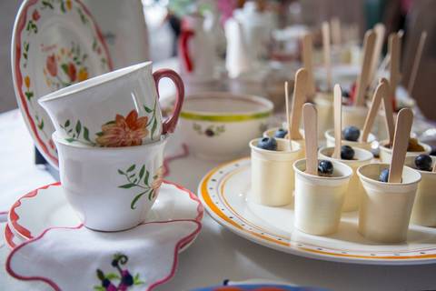 Louças da coleção Westwing dispostas ao lado de uma sobremesa servida em um copinho, mostrando a integração dos produtos no ambiente do evento no Restaurante Carlota em São Paulo.'