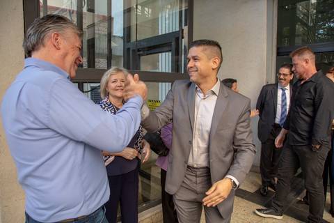 Noivo cumprimentando calorosamente um convidado na entrada do 9º Cartório de Registro Civil da Vila Mariana, em São Paulo, antes da cerimônia de casamento.'