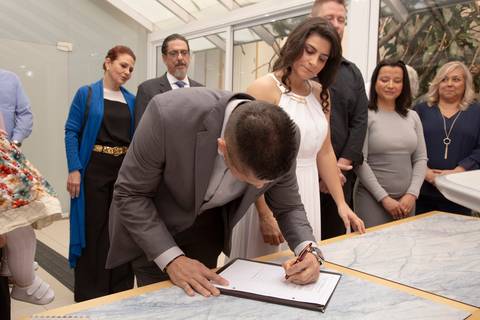 Noivo assinando o documento de casamento com determinação, selando o matrimônio no 9º Cartório de Registro Civil da Vila Mariana, em São Paulo.'