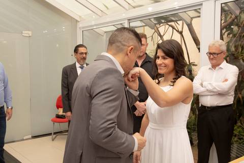 Noivo beijando a mão da noiva com carinho e reverência, um gesto romântico durante a cerimônia de casamento no 9º Cartório da Vila Mariana, São Paulo.'