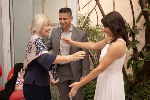 Casal de noivos cumprimentando uma convidada com entusiasmo e gratidão, após a cerimônia de casamento no 9º Cartório da Vila Mariana, São Paulo.'