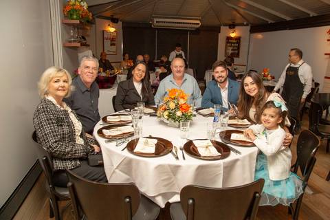 Grupo de convidados posando para uma foto sentados em uma mesa elegantemente arrumada no Restaurante Le Bife em São Paulo, durante a festa de casamento.'