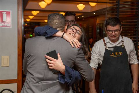 O recém-casado cumprimentando calorosamente um convidado no Restaurante Le Bife em São Paulo, durante a festa de casamento, com um sorriso de satisfação.'