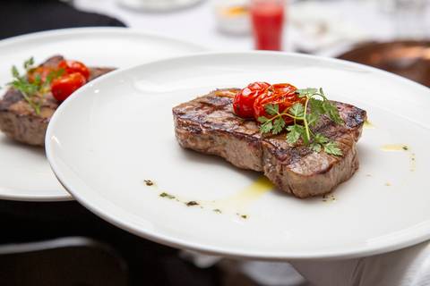 Close-up de um suculento bife, prato principal do Restaurante Le Bife em São Paulo, servido durante a festa de casamento, destacando a especialidade da casa.'