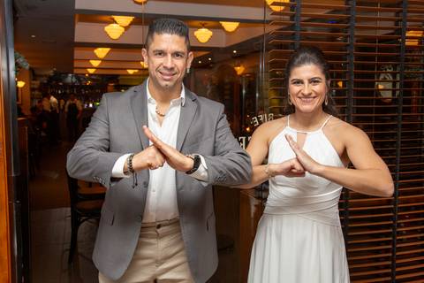 O casal recém-casado fazendo a icônica pose de Kinrai do kung fu dentro do Restaurante Le Bife em São Paulo, um toque pessoal e divertido na festa.'