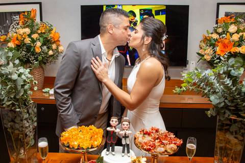 O casal se beijando carinhosamente na mesa do bolo, em um momento romântico e íntimo durante a festa de casamento no Restaurante Le Bife em São Paulo.'