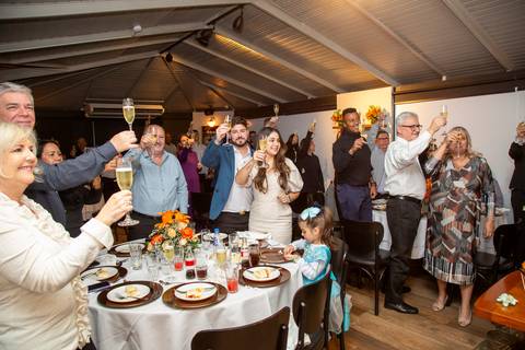 Convidados da festa de casamento levantando suas taças em um brinde coletivo, compartilhando a alegria e a celebração no Restaurante Le Bife em São Paulo.'