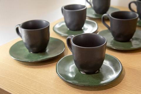 Conjunto de xícaras de porcelana com pires da Porto Brasil, exibidos com elegância na decoração do evento Westwing na loja de Moema, São Paulo.'