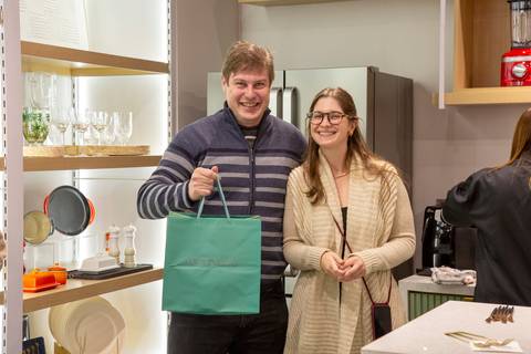 Participante do evento Westwing + Porto Brasil em Moema, São Paulo, sorrindo e posando com o brinde que ganhou no sorteio, demonstrando alegria.'