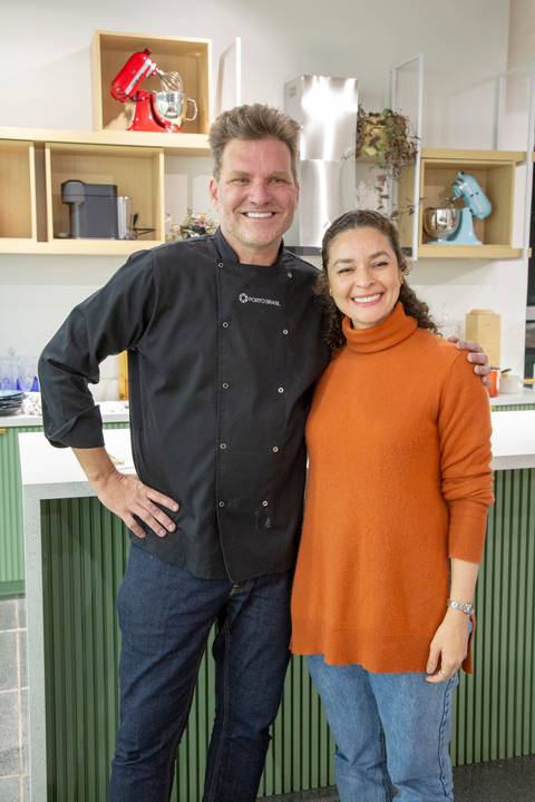 Chef Carlos Bertolazzi em mais uma foto posada com uma convidada, com um gesto amigável, durante o evento culinário na loja Westwing de Moema, São Paulo.'