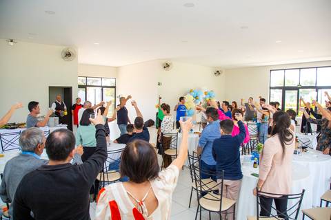 Momento de brinde no salão da festa de 80 anos em Boituva-SP, com todos os convidados levantando seus copos em celebração à aniversariante.'