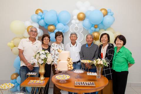 A aniversariante japonesa de 80 anos posando com um grupo de convidados, todos sorrindo, registrando a alegria compartilhada na festa em Boituva-SP.'