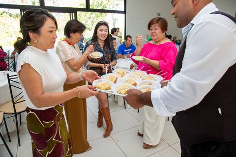 Garçom servindo fatias do bolo de aniversário para os convidados, garantindo que todos desfrutem da sobremesa na festa em Boituva-SP.'