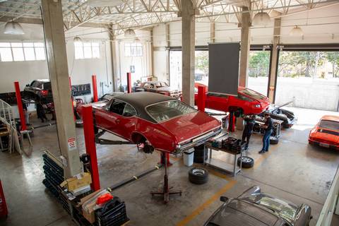 Vista de cima da oficina DAN911 em São Paulo, mostrando a organização do espaço, ferramentas e diversos modelos Porsche estacionados, revelando a estrutura da oficina especializada.'