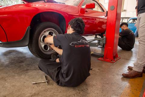 Mecânicos da oficina DAN911 em São Paulo em plena atividade, concentrados em reparos e manutenções em veículos Porsche, mostrando o dinamismo do trabalho.'