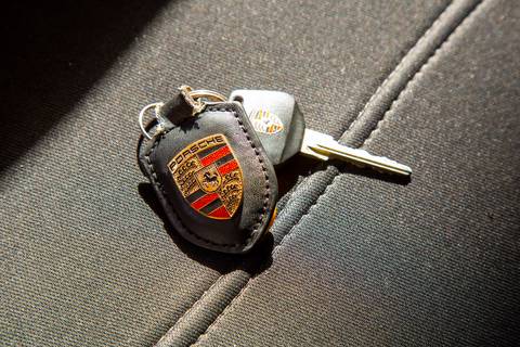 Chave de um Porsche com seu chaveiro icônico da marca em evidência, refletindo a paixão e o cuidado pelos detalhes na oficina DAN911 em São Paulo.'