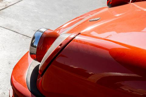 Lateral de um carro Porsche em plano fechado na lanterna frontal, destacando o design clássico e elegante do veículo na oficina DAN911 em São Paulo.'