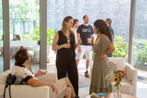 A futura mãe conversando com convidados em área interna do chá de bebê em São Paulo, enquanto o futuro pai interage com outros convidados na área externa, mostrando a movimentação do evento.'