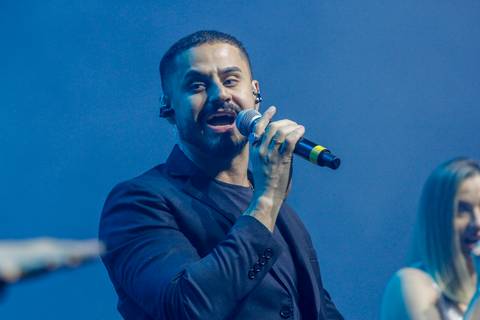 Cantor principal da banda performando com energia no palco do Espaço Unimed em São Paulo, durante o show pós-evento do GPA, agitando o público presente.'