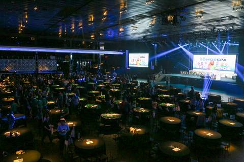 Visão lateral superior do Espaço Unimed em São Paulo, exibindo a decoração do evento do GPA, com a disposição das cadeiras e o palco ao fundo, preparado para receber os mais de mil convidados.'